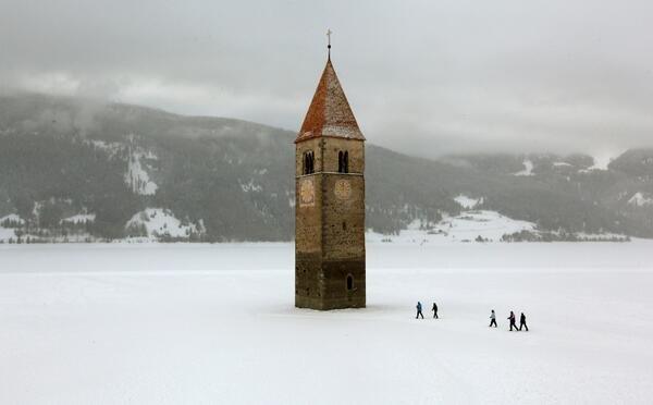 Church steeple peeking out of a frozen lake in the village of Graun