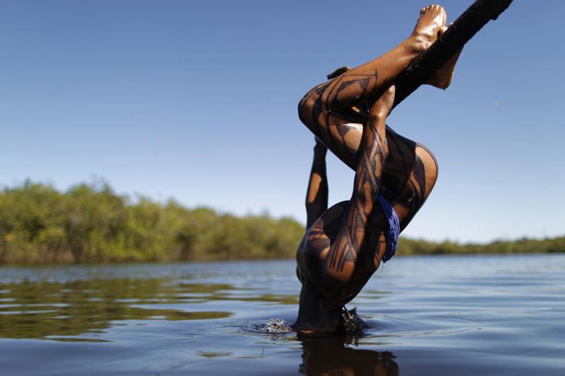 A Yawalapiti boy dips his head into the Xingu River in the Xingu National Park