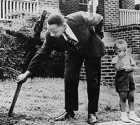 Martin Luther King Jr removing a burned cross from his front yard with his son at his side in 1960