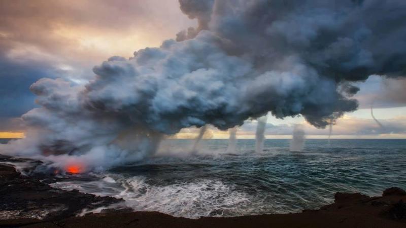 Multiple waterspouts touching down where the lava flow meets the ocean at Kilauea