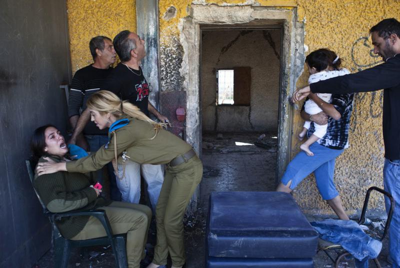 Israelis react and run for cover as a siren sounds warning of incoming rockets