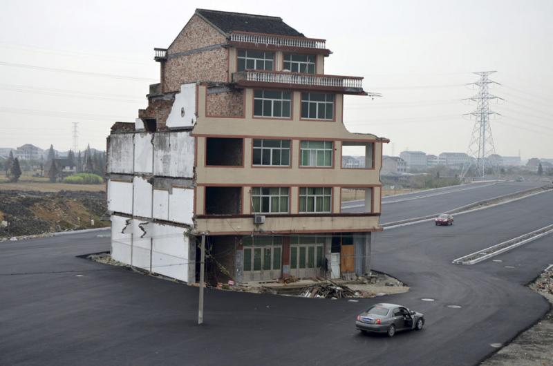 A car stops beside a house in the middle of a newly built road in Wenling, Zhejiang province