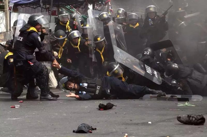 أفضل صور العالم لعام ٢٠١٤ حسب WSJ - شرطي يساعد شرطي آخر مصاب بعد انفجار قنبلة من قبل متظاهرين في بانكوك