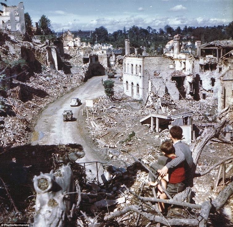 The aftermath of D-Day as two boys watch from a tree while American soldiers drive through Saint Lo in France #History