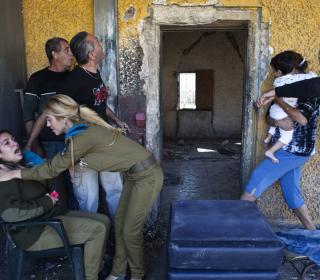 Israelis react and run for cover as a siren sounds warning of incoming rockets